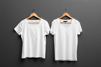 Hangers with blank t-shirts on grey background. Mockup for design