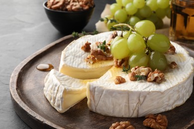 Brie cheese served with grapes, walnuts and honey on grey table, closeup