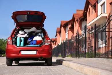 Family car with open trunk full of luggage in city. Space for text
