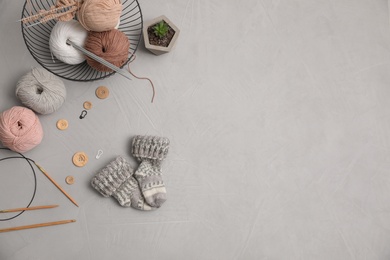 Flat lay composition with threads and knitted mittens on grey background, space for text. Engaging hobby
