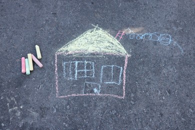 Child's house drawing and pieces of color chalk on asphalt, flat lay