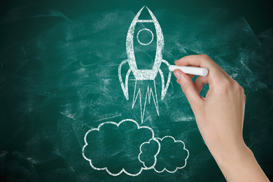 Business startup concept. Woman drawing rocket on chalkboard, closeup