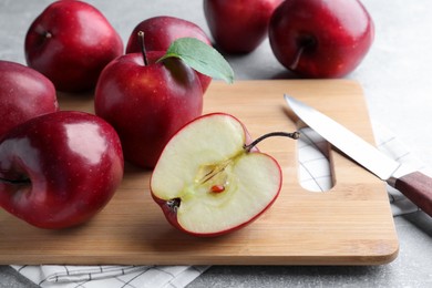Fresh ripe red apples and knife on light grey table, closeup