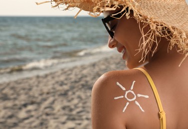 Photo of Young woman with sun protection cream on shoulder at beach