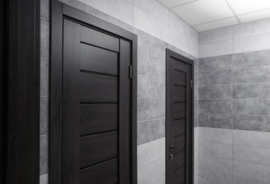 Photo of Public toilet interior with stylish doors and tiles