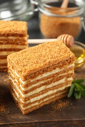 Photo of Delicious layered honey cake on wooden board, closeup