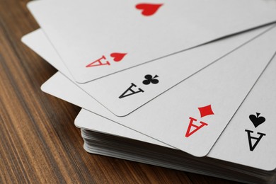 Four aces playing cards on wooden table, closeup