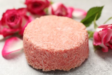 Photo of Solid shampoo bar and roses on light grey table, closeup. Hair care