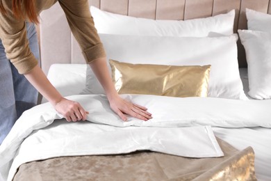 Woman making bed with stylish linens in room, closeup