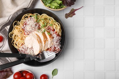 Delicious pasta with tomato sauce, chicken and parmesan cheese on white tiled table, flat lay. Space for text