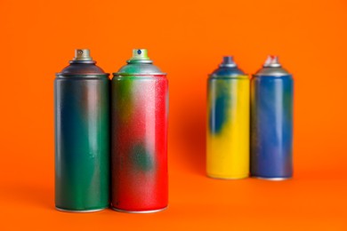 Photo of Used cans of spray paints on orange background