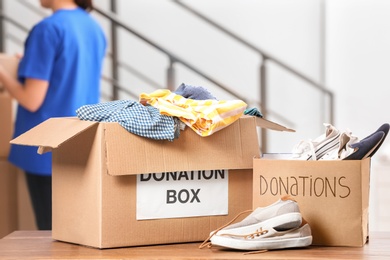 Photo of Donation boxes with clothes and shoes on table indoors