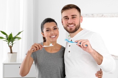 Young couple with toothbrushes in bathroom. Teeth care