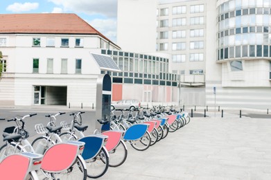 Many bicycles and station on city street. Bike rental fleet