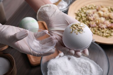 Woman in gloves making bath bomb at table, closeup