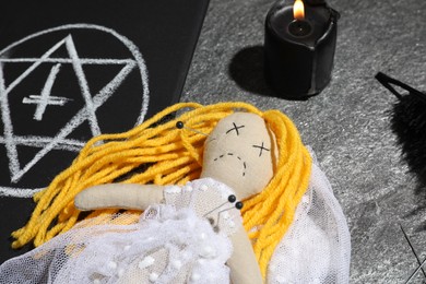 Bride voodoo doll with pins surrounded by ceremonial items on grey table