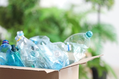 Cardboard box with used plastic bottles on blurred background. Recycling problem