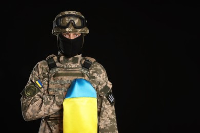 Soldier in military uniform with Ukrainian flag on black background. Space for text