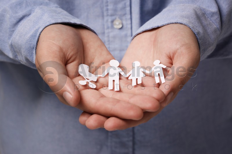 Man holding paper family figures, closeup. Insurance concept