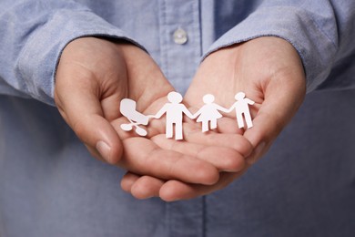 Man holding paper family figures, closeup. Insurance concept