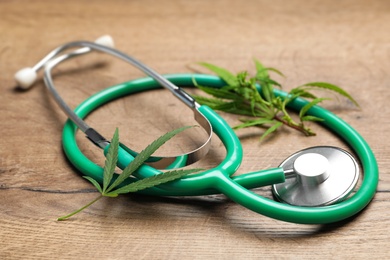 Hemp leaves and stethoscope on wooden table