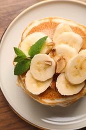 Tasty pancakes with sliced banana on wooden table, closeup