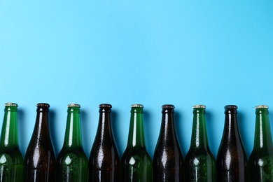 Photo of Bottles of beer on light blue background, flat lay. Space for text