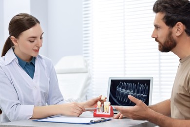Photo of Doctor showing patient educational model of dental implant in clinic