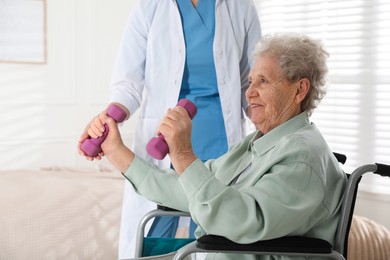 Senior woman in wheelchair doing physical exercise indoors. Home health care service