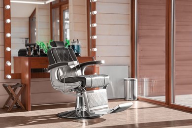Stylish hairdresser's workplace with professional armchair and large mirror in barbershop. Interior design