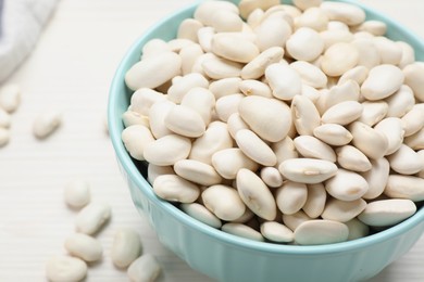 Raw beans and bowl on white table, closeup