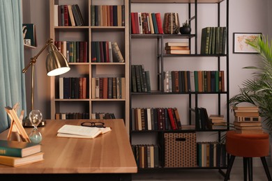 Wooden table and collection of different books on shelves in home library