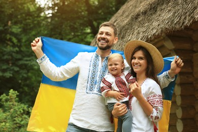 Happy family in national clothes with flag of Ukraine outdoors