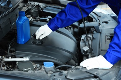 Photo of Worker checking motor oil level in car, closeup