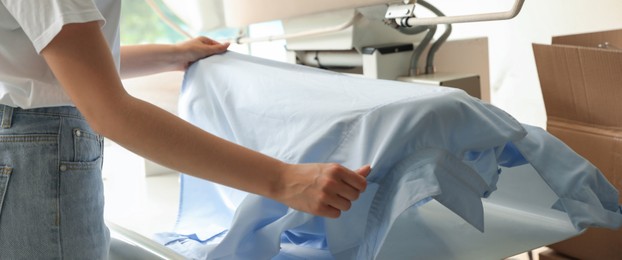 Closeup view of female worker using ironing press, banner design. Dry-cleaning service
