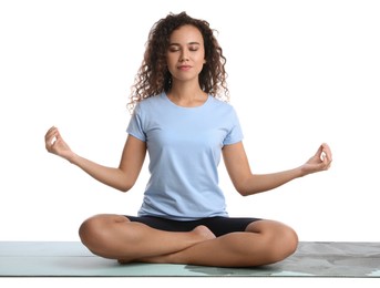 Beautiful African-American woman meditating on yoga mat against white background