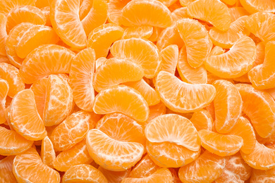 Photo of Fresh juicy tangerine segments as background, top view