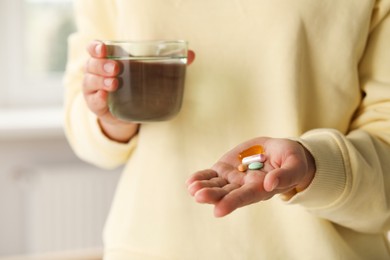 Photo of Young woman with glass of water and dietary supplement pills indoors, closeup