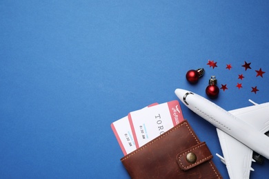Toy airplane, festive decor, airline tickets and space for text on blue background, flat lay. Christmas vacation