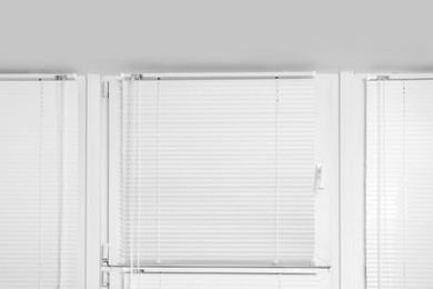 Window with closed white horizontal blinds indoors, low angle view