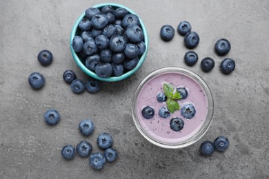 Photo of Glass of blueberry smoothie with mint and fresh berries on grey table, flat lay