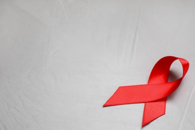 Top view of red ribbon on grey stone background, space for text. AIDS disease awareness