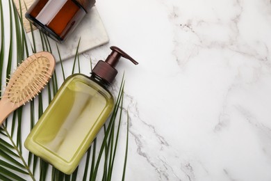 Photo of Shampoo bottles, hair brush and green leaf on white marble table, flat lay. Space for text