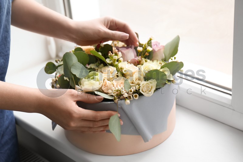 Female florist holding box with flowers indoors