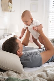 Father with his cute baby on bed at home. Happy family