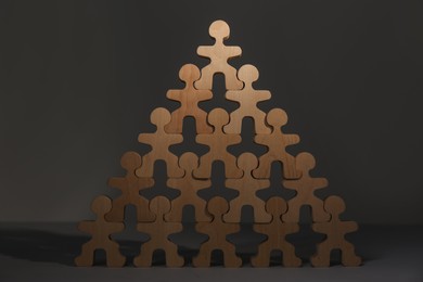 Photo of Recruitment process, job competition concept. Pyramid of wooden human figures with noticeable one on top as prime applicant on grey table