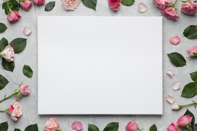 Flat lay composition with blank canvas and beautiful roses on grey marble background. Mockup for design