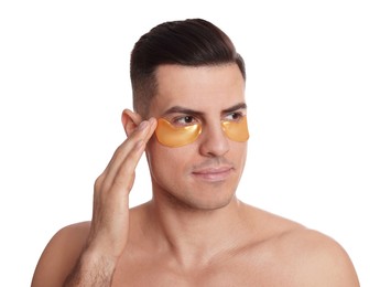 Man applying golden under eye patch on white background