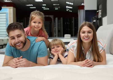 Happy family lying on new orthopedic mattress in store