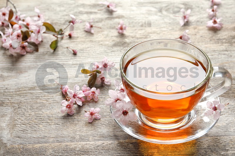 Cup of tea and blossoming flowers on wooden background